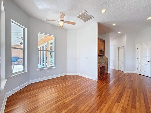 spare room featuring hardwood / wood-style flooring, baseboards, visible vents, and ceiling fan