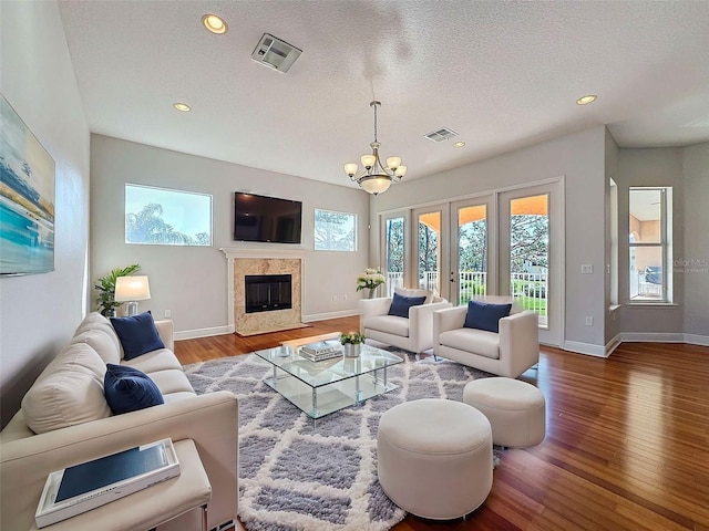 living area featuring recessed lighting, wood finished floors, visible vents, and a high end fireplace