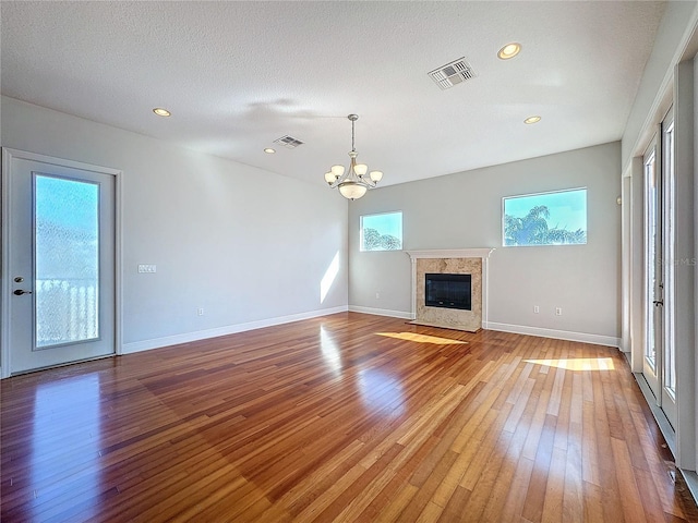 unfurnished living room featuring baseboards, light wood-style floors, visible vents, and a premium fireplace