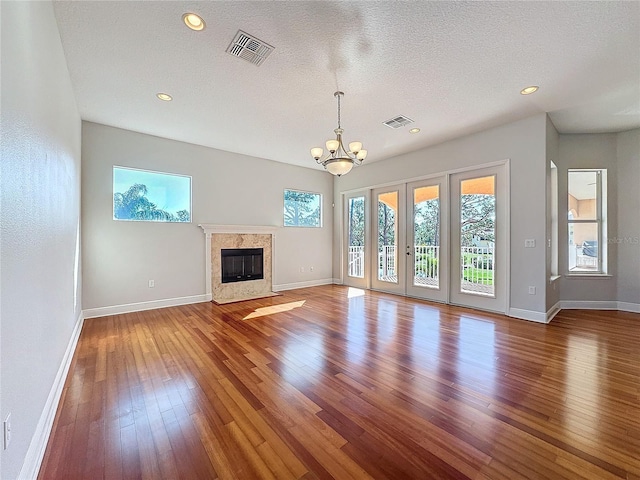 unfurnished living room featuring hardwood / wood-style floors, visible vents, baseboards, and a premium fireplace