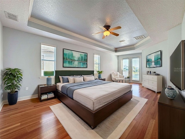 bedroom with visible vents, a raised ceiling, and access to outside