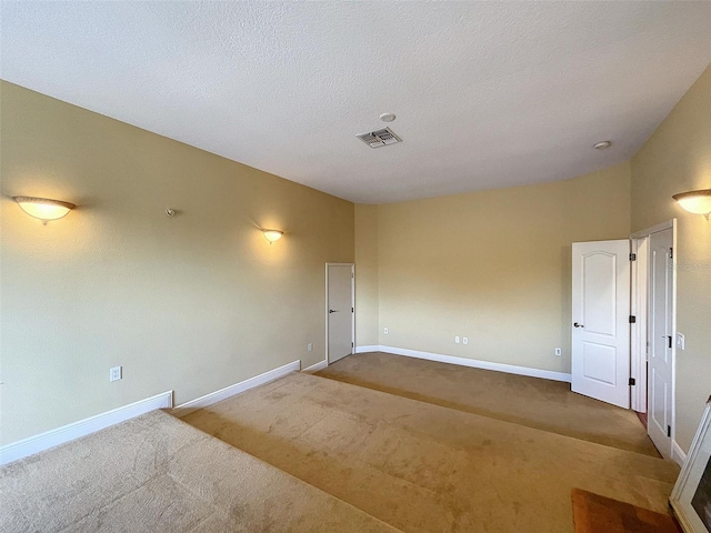 unfurnished room featuring carpet flooring, baseboards, visible vents, and a textured ceiling