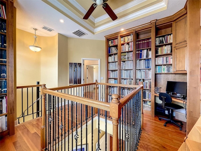 office area with a raised ceiling, crown molding, wood finished floors, and visible vents