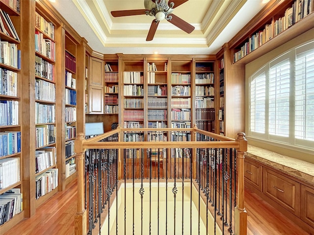 living area with bookshelves, crown molding, and a tray ceiling