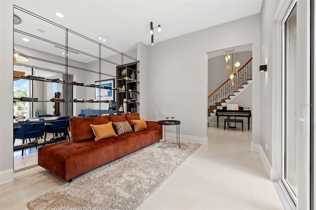 living room with stairs, tile patterned flooring, and baseboards