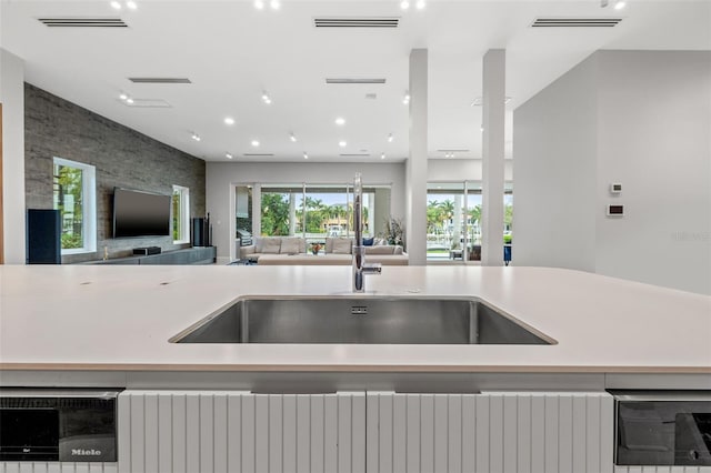 kitchen with open floor plan, light countertops, visible vents, and an accent wall