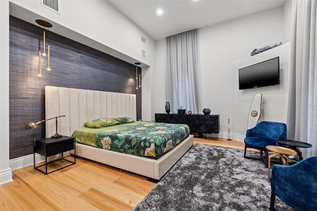 bedroom featuring wood finished floors, visible vents, and baseboards