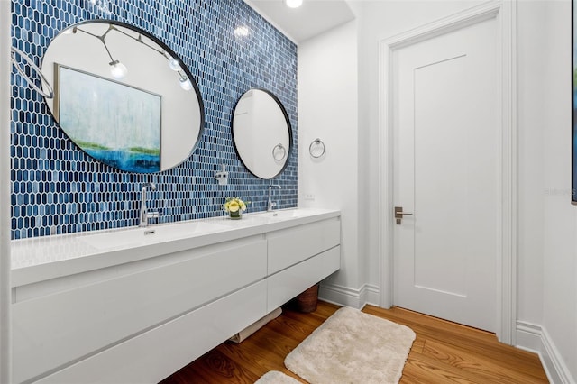 bathroom featuring double vanity, a sink, baseboards, and wood finished floors