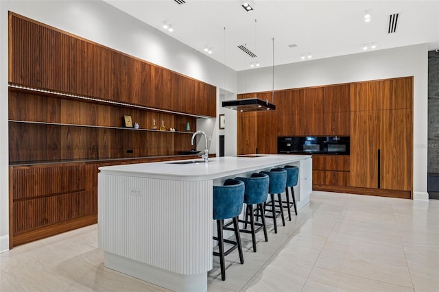 kitchen with modern cabinets, light countertops, a large island with sink, open shelves, and a sink