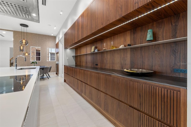 kitchen with dark countertops, modern cabinets, hanging light fixtures, open shelves, and a sink