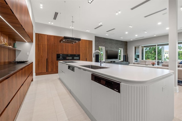 kitchen featuring modern cabinets, brown cabinets, range hood, light countertops, and a sink