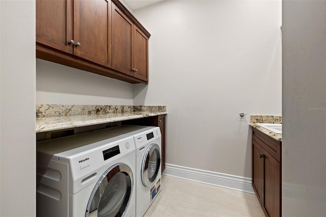 washroom featuring baseboards, cabinet space, washing machine and clothes dryer, and light tile patterned floors