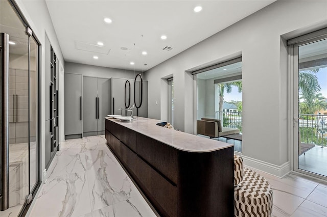 kitchen with light countertops, visible vents, a healthy amount of sunlight, an island with sink, and modern cabinets