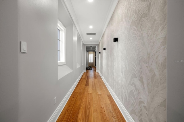 hallway featuring recessed lighting, visible vents, baseboards, ornamental molding, and light wood-type flooring