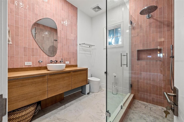 full bathroom featuring marble finish floor, tile walls, toilet, a shower stall, and vanity