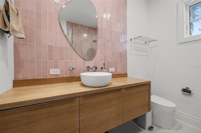 bathroom with toilet, marble finish floor, vanity, and decorative backsplash