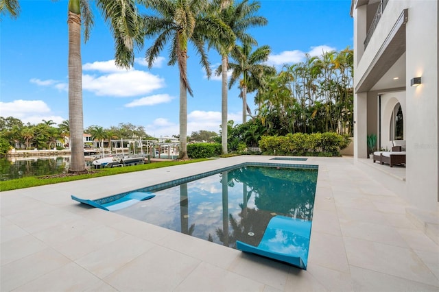 outdoor pool with a water view and a patio