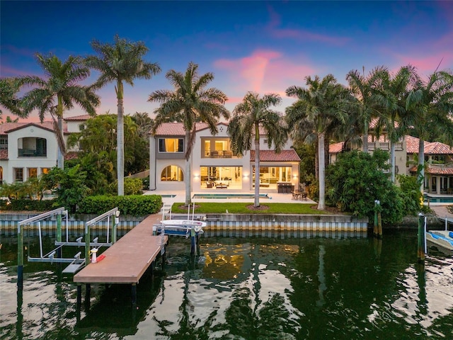 view of dock featuring a water view, a balcony, boat lift, and a patio