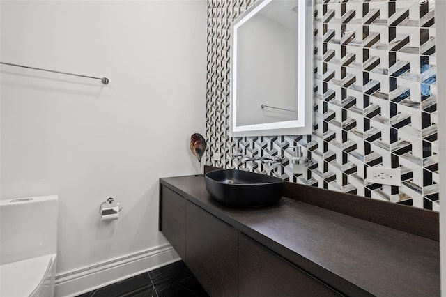 half bath with baseboards, a sink, and toilet