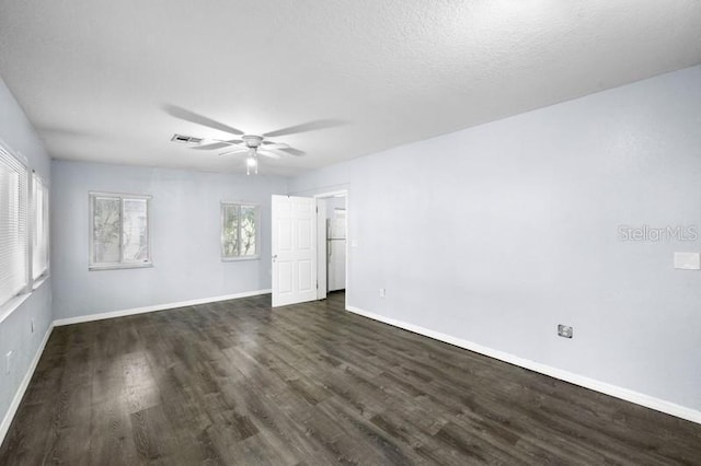 empty room featuring a textured ceiling, dark wood-type flooring, and ceiling fan