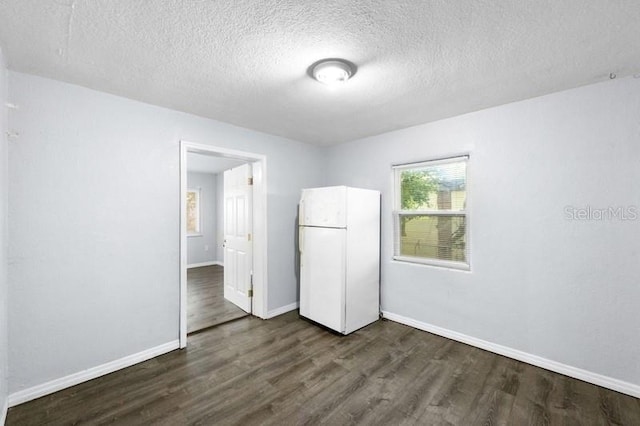 empty room featuring a textured ceiling and dark wood-type flooring