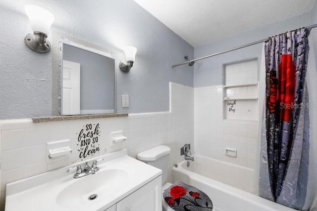 full bathroom featuring toilet, vanity, tile walls, shower / bathtub combination with curtain, and a textured ceiling