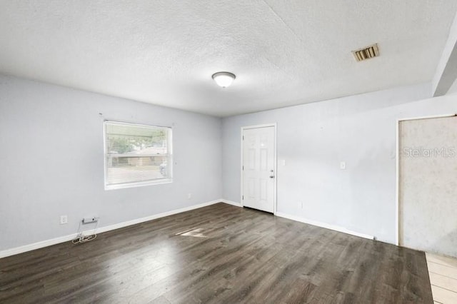 unfurnished room with a textured ceiling and dark hardwood / wood-style flooring