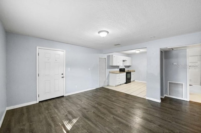 unfurnished living room with a textured ceiling and light hardwood / wood-style floors