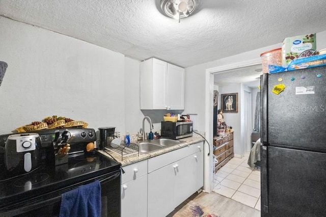 kitchen featuring light hardwood / wood-style floors, black appliances, sink, white cabinetry, and a textured ceiling