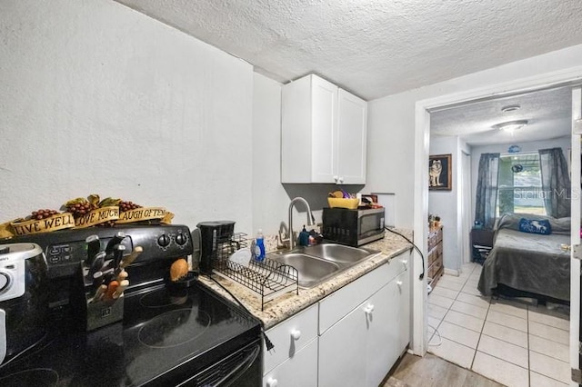 kitchen featuring sink, black electric range oven, a textured ceiling, white cabinets, and light stone counters