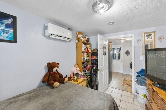 bedroom featuring a wall mounted AC, light tile patterned flooring, and a textured ceiling