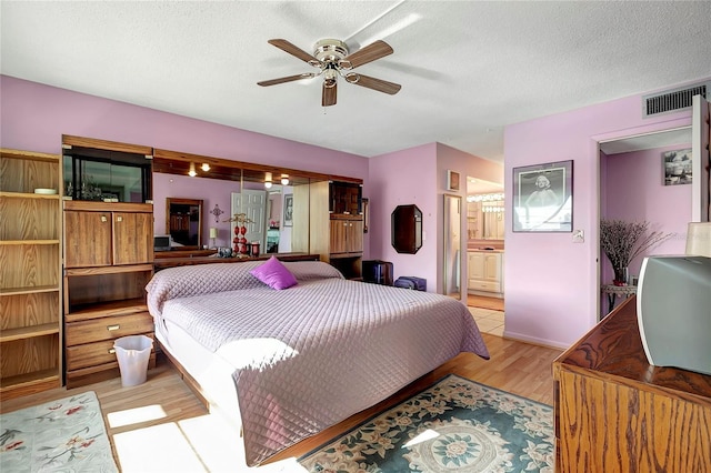 bedroom with connected bathroom, ceiling fan, light hardwood / wood-style floors, and a textured ceiling