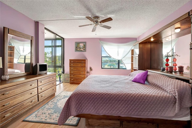 bedroom with a textured ceiling, light wood-type flooring, and ceiling fan