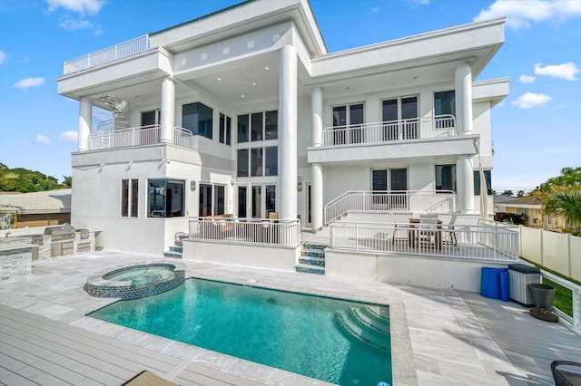 rear view of house featuring a balcony and a swimming pool with hot tub