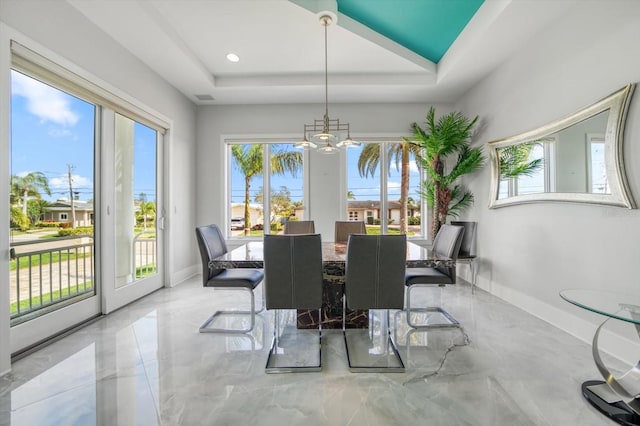 dining room featuring a tray ceiling, a notable chandelier, and light tile patterned floors