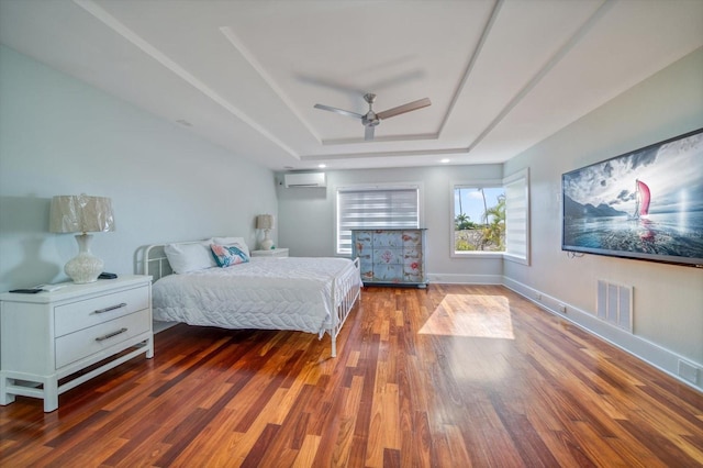 unfurnished bedroom with ceiling fan, a wall mounted AC, a raised ceiling, and wood-type flooring