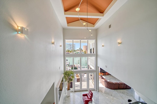 stairway featuring tile patterned floors, high vaulted ceiling, and a water view