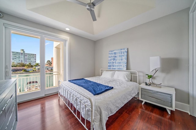 bedroom featuring a tray ceiling, ceiling fan, hardwood / wood-style flooring, and access to outside