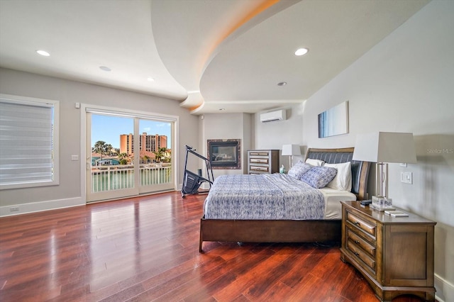 bedroom with dark hardwood / wood-style floors, access to outside, and a wall unit AC