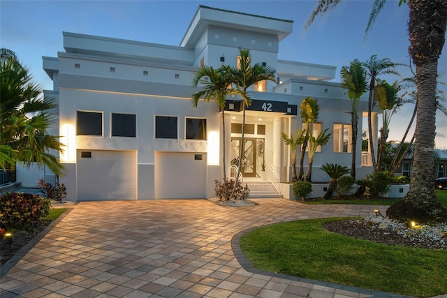 view of front of property featuring a garage, decorative driveway, and stucco siding