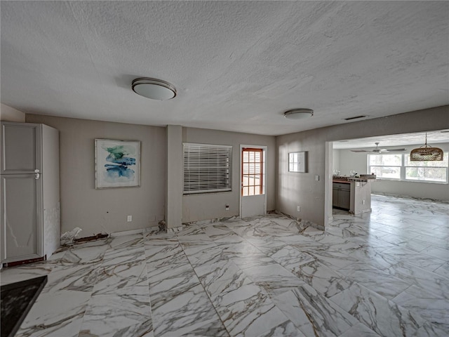 unfurnished living room featuring ceiling fan, a healthy amount of sunlight, and a textured ceiling