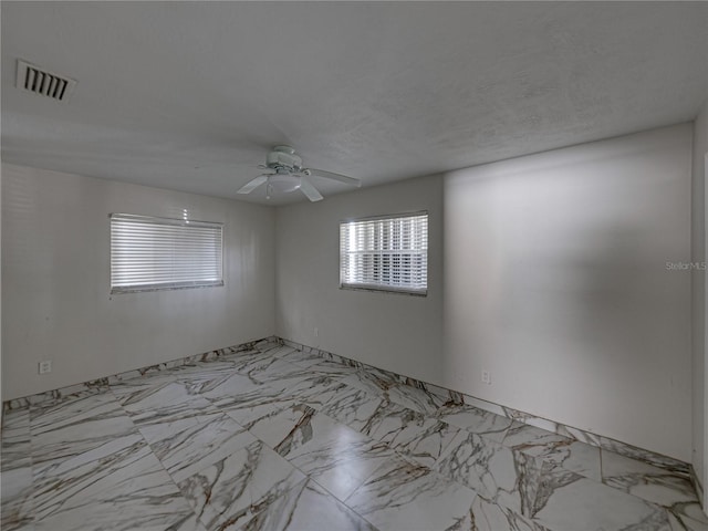 spare room featuring marble finish floor, ceiling fan, and visible vents