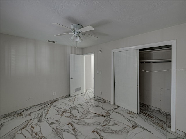 unfurnished bedroom with ceiling fan, a textured ceiling, and a closet