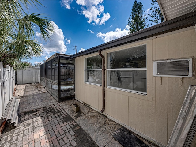 view of side of property featuring a wall mounted air conditioner, a patio, and a lanai