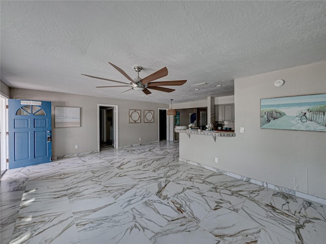 unfurnished living room with ceiling fan and a textured ceiling