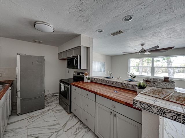 kitchen featuring wood counters, gray cabinetry, a textured ceiling, stainless steel appliances, and ceiling fan