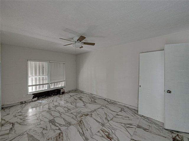 empty room with ceiling fan and a textured ceiling