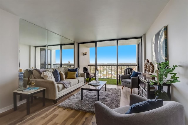 living room featuring baseboards, floor to ceiling windows, and wood finished floors