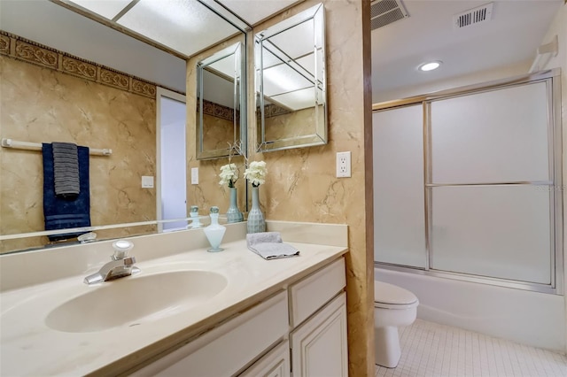 full bath featuring toilet, vanity, visible vents, combined bath / shower with glass door, and tile patterned floors