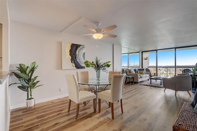 dining room with baseboards, wood finished floors, a ceiling fan, and floor to ceiling windows